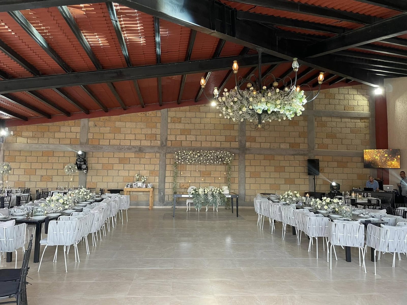 Salón principal de El Realejo de día, con techo de teja y vigas de acero, mesas montadas y candil de hierro